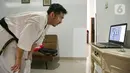 Charlie (28) instruktur karate menyaksikan para muridnya berlatih secara virtual di Jakarta, Sabtu (13/2/2021). Sejak bulan Maret murid-murid berlatih di rumah secara vitual guna mencegah penyebaran virus Covid-19. (Liputan6.com/Faizal Fanani)