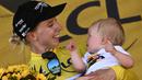 Pebalap Tim DSM, Lorena Wiebes menggendong anaknya saat merayakan kemenagannya di etape pertama Tour de France Wanita 2022 yang menempuh jarak sepanjang 81,6 km dari Tour Eiffel hingga Champs-Elysees, Paris pada 24 Juli 2022. (AFP/Jeff Pachoud)