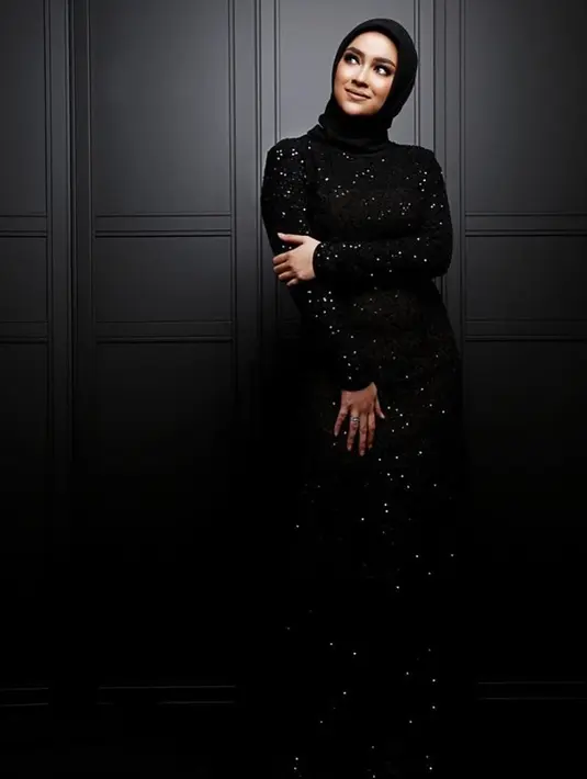 Tak hanya bergaya santai, istri Donny Michael juga memancarkan auranya kala pakai gaun panjang dan hijab hitam serta makeup tebal. (Liputan6.com/IG/aryanifitriana24)