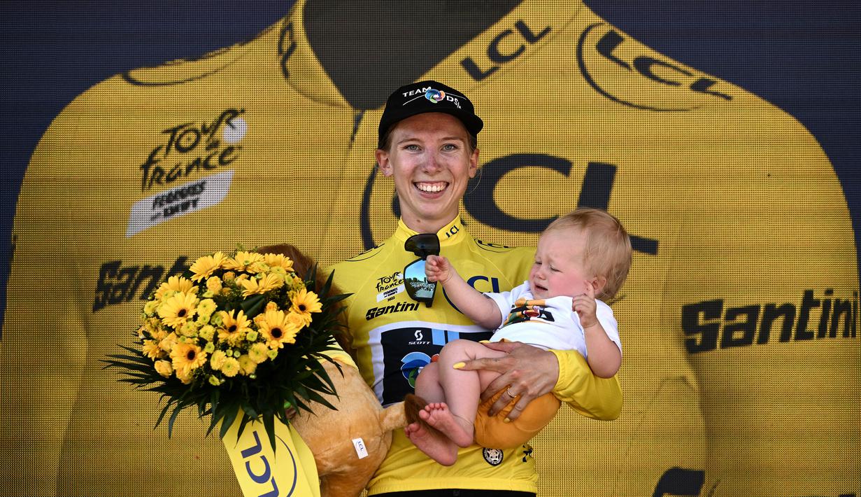 Pebalap Tim DSM, Lorena Wiebes menggendong anaknya saat merayakan kemenagannya di etape pertama Tour de France Wanita 2022 yang menempuh jarak sepanjang 81,6 km dari Tour Eiffel hingga Champs-Elysees, Paris pada 24 Juli 2022. (AFP/Jeff Pachoud)