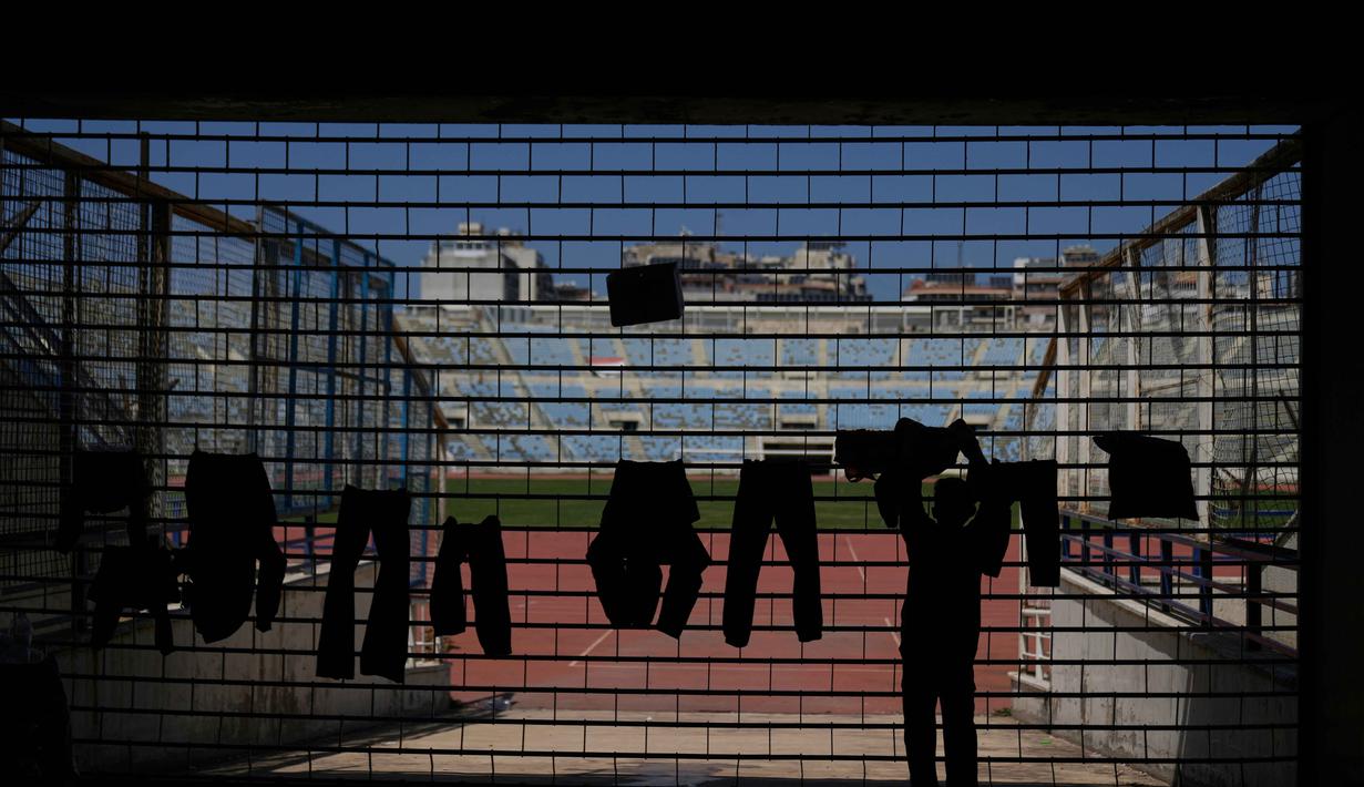 Sementara, jumlah pengungsi di Lebanon telah melampaui 1,1 juta jiwa, sebagian besar harus hidup dengan akses kebutuhan pokok yang terbatas. Tampak dalam foto, seorang anak laki-laki pengungsi menjemur pakaian keluarganya di dalam Camille Chamoun Sports City Stadium, yang telah diubah menjadi tempat penampungan bagi orang-orang yang melarikan diri dari serangan udara Israel di Lebanon selatan, Beirut, Lebanon, Rabu 8 April 2026. (AP Photo/Bilal Hussein)
