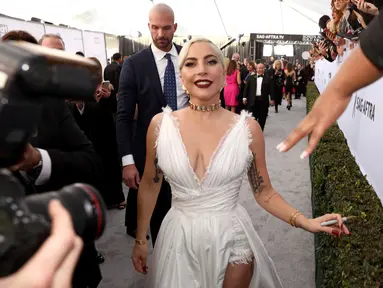 Lady Gaga menyapa penggemar saat menghadiri acara 25th Screen Actors Guild Awards di Los Angeles, California, AS (28/1). Lady Gaga tampil anggun menggenakan gaun putih dengan belahan hingga paha kreasi Dior Haute Couture. (AP Photo/Jordan Strauss)