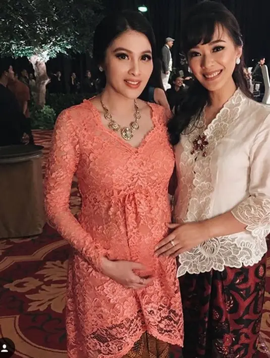 Sandra Dewi tampil simple dengan kebaya lace warna orange, ia menambah kalung sebagai aksesorinya. (@sandradewi88)