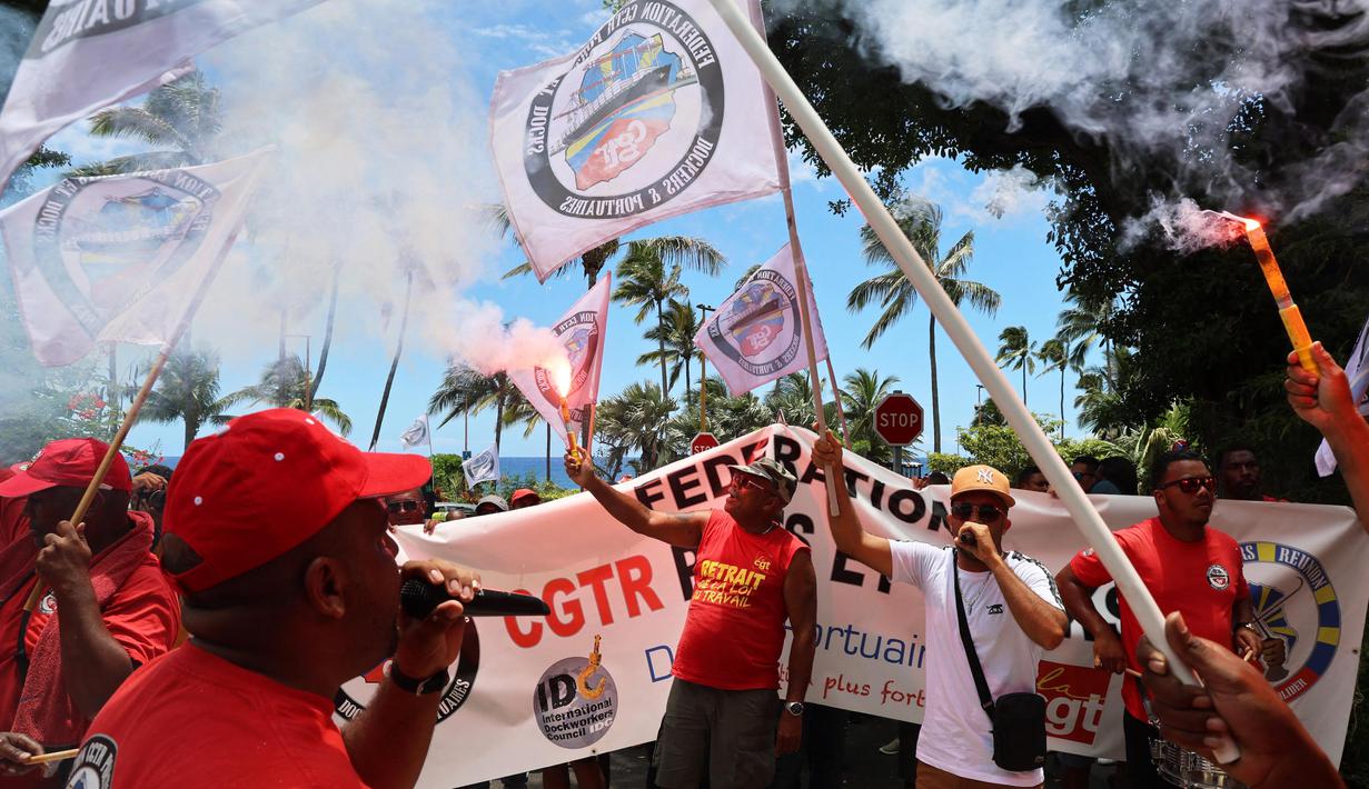 Para pengunjuk rasa menyalakan suar saat aksi demonstrasi pada hari kelima demonstrasi nasional yang diselenggarakan sejak awal tahun, menentang perombakan pensiun yang sangat tidak populer, di Saint-Denis-de-la-Reunion, di pulau seberang lautan Prancis, La Reunion, Kamis (16/2/2023). (Richard BOUHET/AFP)