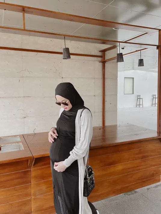 Mengenang masa hamil anak pertama, Dinda Hauw unggah foto OOTD dengan dress hitam panjang yang dilapisi dengan cardigan berwarna abu-abu. Cocok untuk ibu hamil yang ingin tampil kasual dan simple. (instagram/dindahw)
