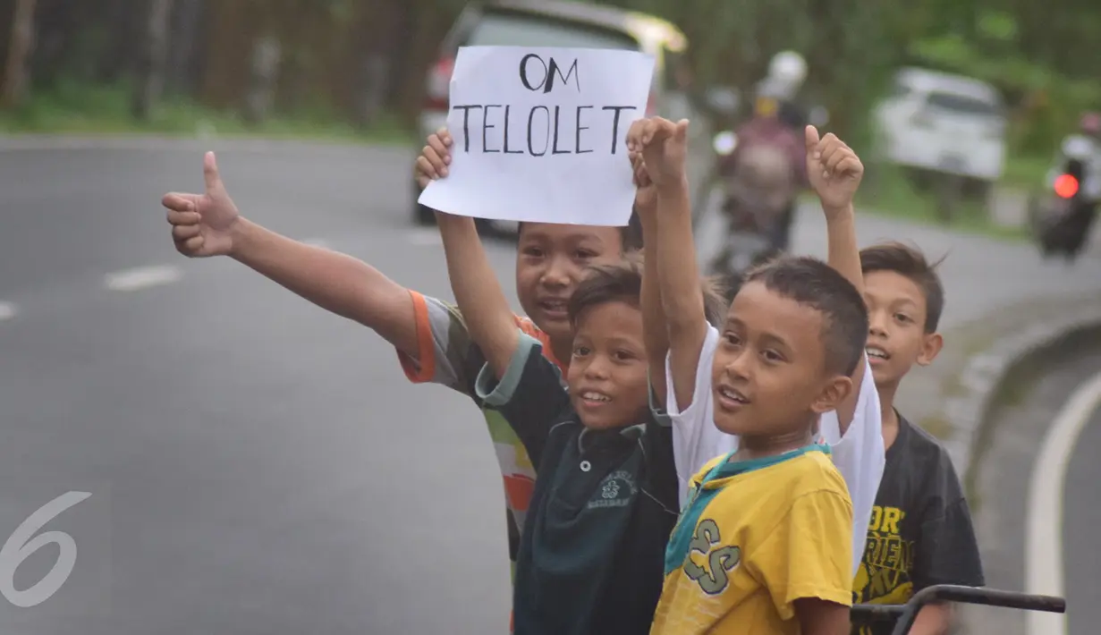 Anak-anak  saat meminta bunyi klakson telolet ke bus yang lewat jalan raya A Yani Surakarta, Solo, Kamis (22/12). Fenomena ini mendunia setelah beberapa artis dan tokoh terkenal dunia berkomentar di media sosial. (Liputan6.com/Gholib)