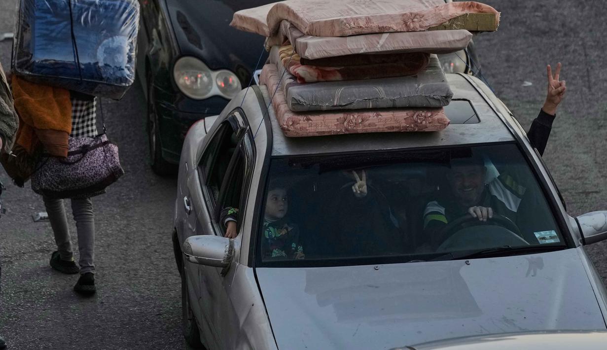Warga berbondong-bondong meninggalkan rumah mereka menggunakan kendaraan yang dipenuhi barang berharga, kemacetan panjang di sejumlah jalur utama tak terhindarkan. Tampak dalam foto, sebuah keluarga mengacungkan tanda kemenangan saat mereka melarikan diri dari serangan udara Israel di Dahiyeh, pinggiran selatan Beirut, Lebanon, Kamis 5 Maret 2026. (AP Photo/Bilal Hussein)