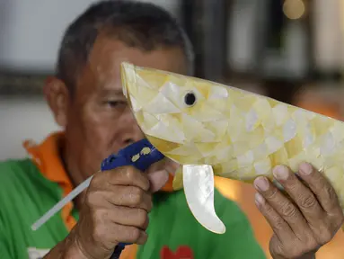 Perajin menyelesaikan pembuatan kerajinan tangan dari kulit kerang di Pamulang 2, Tangerang Selatan, Banten, Senin (20/7/2020). Aneka kerajinan tangan dengan motif bunga hingga ikan tersebut diolah dari limbah kulit kerang. (merdeka.com/Dwi Narwoko)