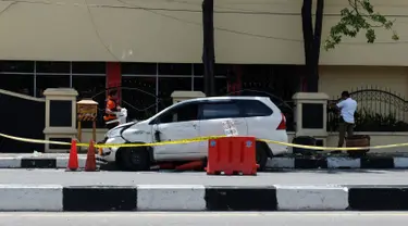 Petugas kepolisian memeriksa mobil yang digunakan terduga teroris setelah serangan di luar markas polisi di Pekanbaru, Riau (16/5). Empat pelaku penyerangan ditembak dan tewas ketika mereka melakukan serangan.  (AFP Photo/Dedy Sutisna)