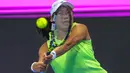 Kalah dari petenis No.2 dunia Iga Swiatek, langkah tunggal putri Indonesia, Janice Tjen, di Qatar Total Energies Open 2026 terhenti di babak kedua. Tampak dalam foto, petenis tunggal putri Indonesia, Janice Tjen memukul bola balasan saat melawan Iga Swiatek (Polandia) pada babak kedua turnamen Qatar Open di Doha, 10 Februari 2026. (Karim JAAFAR/AFP)