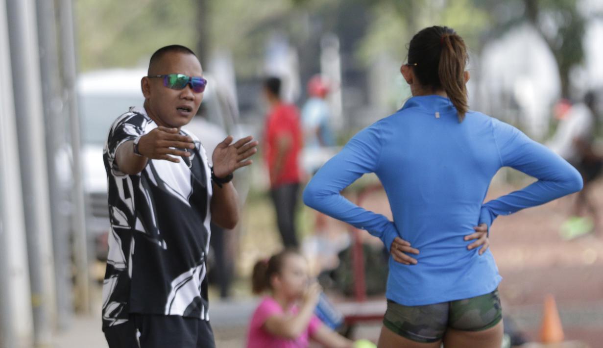 Pelatih lari gawang, Fitri Ongky Haryadi, memberi arahan kepada Emilia Nova saat sesi latihan di Stadion Madya, Jakarta, Senin (7/9). Meski baru sembuh dari cedera, Emilia Nova tetap mengincar medali emas di SEA Games 2019. (Bola.com/M Iqbal Ichsan)