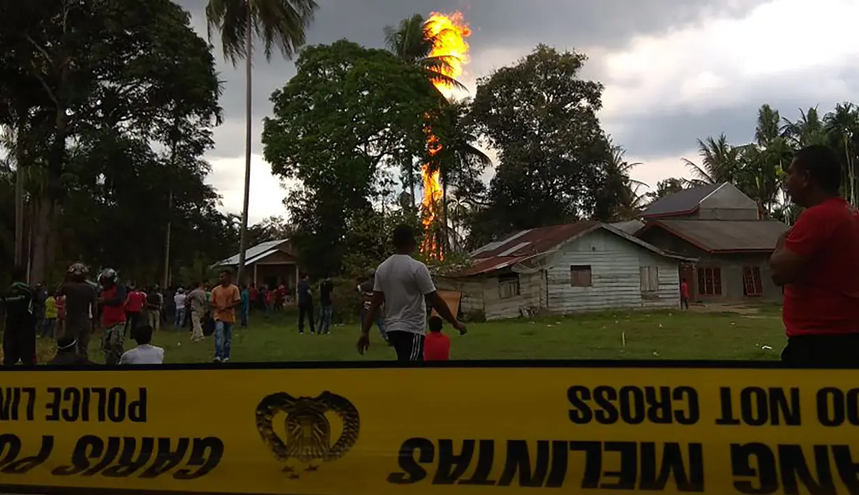 Warga berkumpul melihat kebakaran yang melanda pengeboran sumur minyak ilegal yang dikelola masyarakat di Peureulak, Provinsi Aceh, Rabu (25/4). Sumur minyak yang meledak ini diduga milik warga setempat bernama Nazaruddin. (ILYAS ISMAIL/AFP)