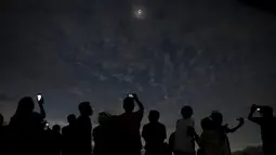 Sejumlah orang melihat dan mengambil gambar dari fenomena Gerhana Matahari Total (GMT) di pantai di pulau Ternate, Indonesia, Rabu (9/3/2015). (REUTERS / Beawiharta)