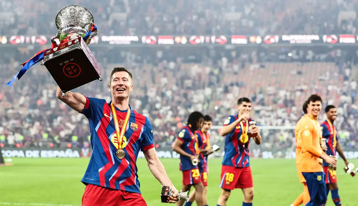 Pemain Barcelona, Robert Lewandowski merayakan gelar juara Piala Super Spanyol 2026 setelah mengalahkan Real Madrid dengan skor 3-2 dalam laga final yang berlangsung di King Abdullah Stadium, Jeddah, Arab Saudi, Minggu (11/01/2026) waktu setempat. (AFP/Fadel Senna)