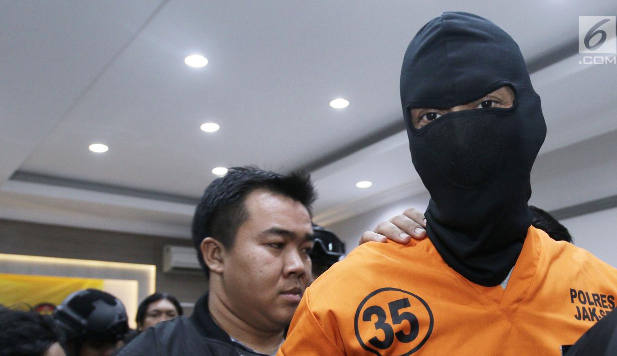 Aktor Tora Sudiro (kenakan penutup wajah hitam) saat dihadirkan dalam jumpa pers kepemilikan psikotropika di Mapolres Jakarta Selatan, Jumat (04/08). Tora dijerat dengan UU Psikotropika tahun 1997 pasal 62. (Liputan6.com/Herman Zakharia)