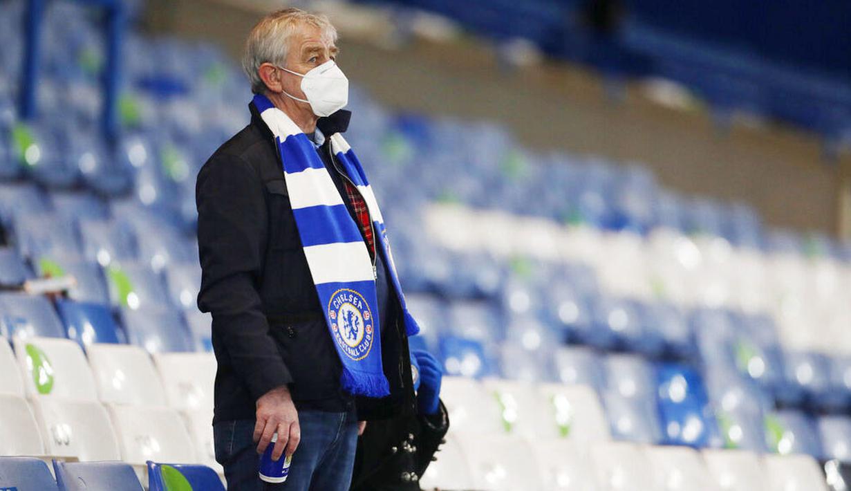 Suporter Chelsea mamakai masker saat menyaksikan pertandingan Chelsea melawan Leeds United pada laga Liga Inggris di Stadion Stamford Bridge, Sabtu (5/12/2020). (Matthew Childs/Pool via AP)