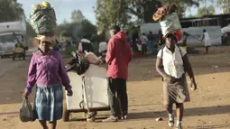 Dua perempuan membawa berbagai barang di kepala mereka saat mereka berjalan di pinggiran kota padat Mbare di Harare, Zimbabwe, Rabu, (26/2/2020). Emmerson Mnangagwa adalah presiden Zimbabwe saat ini. (AP Photo/Tsvangirayi Mukwazhi)