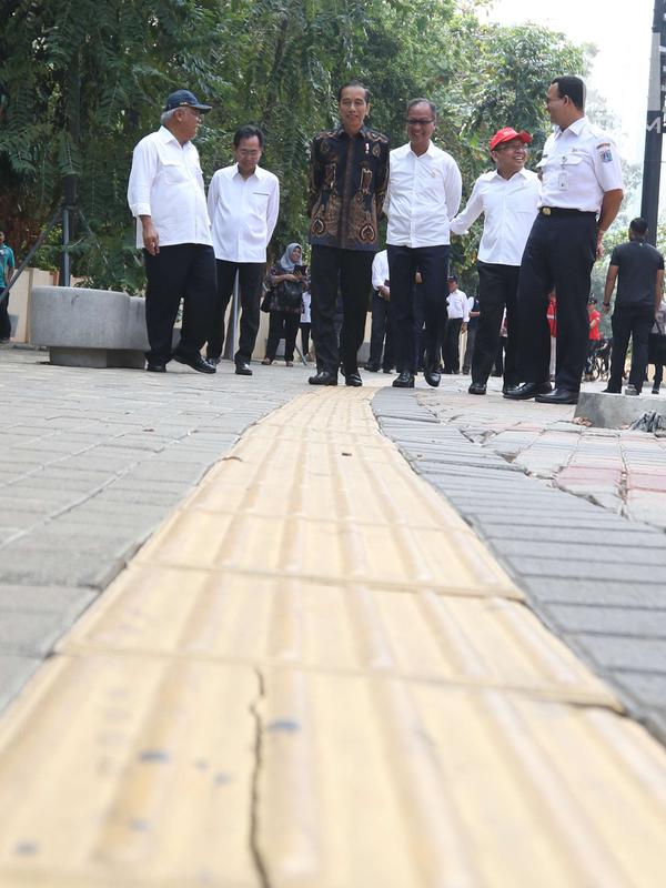 Presiden Joko Widodo (Jokowi) melihat kondisi fasilitas jalur penuntun dan petunjuk bagi disabilitas di Kompleks Gelora Bung Karno, Senayan, Selasa (16/10). Jokowi didampingi sejumlah menteri dan Gubernur DKI Anies Baswedan. (Liputan6.com/Angga Yuniar)