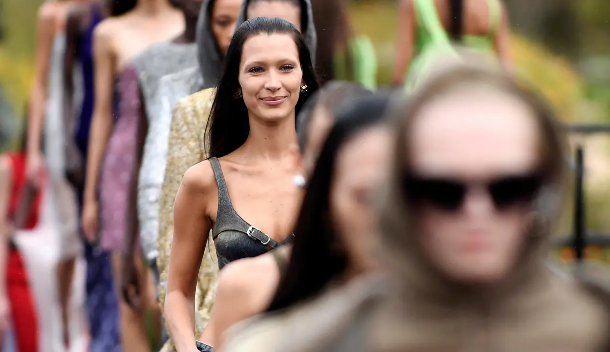 Bella Hadid mengenakan kreasi untuk koleksi busana ready-to-wear Spring/Summer 2023 dari Givenchy yang dipresentasikan selama Paris Fashion Week di Paris pada Minggu, 2 Oktober 2022. Roknya menampilkan desain panel yang tertekan sementara atasan mikronya dihiasi dengan gesper logam dan detail potongan. (AFP/Julien De Rosa)