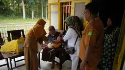 Tenaga kesehatan Siti Nurjanah (kiri) dibantu rekan-rekannya memberikan vaksin campak kepada seorang anak dalam kampanye vaksinasi campak dari rumah ke rumah menyusul wabah di Sumenep, Pulau Madura, Jawa Timur, Senin 8 September 2025. (AP Photo/Dita Alangkara)