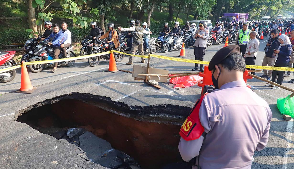 Pengendara melintas di sisi ruas jalan yang ditutup sebagian akibat amblas di Jalan Raya Lenteng Agung, Jakarta Selatan, Jumat (29/5/2026). (merdeka.com/Arie Basuki)