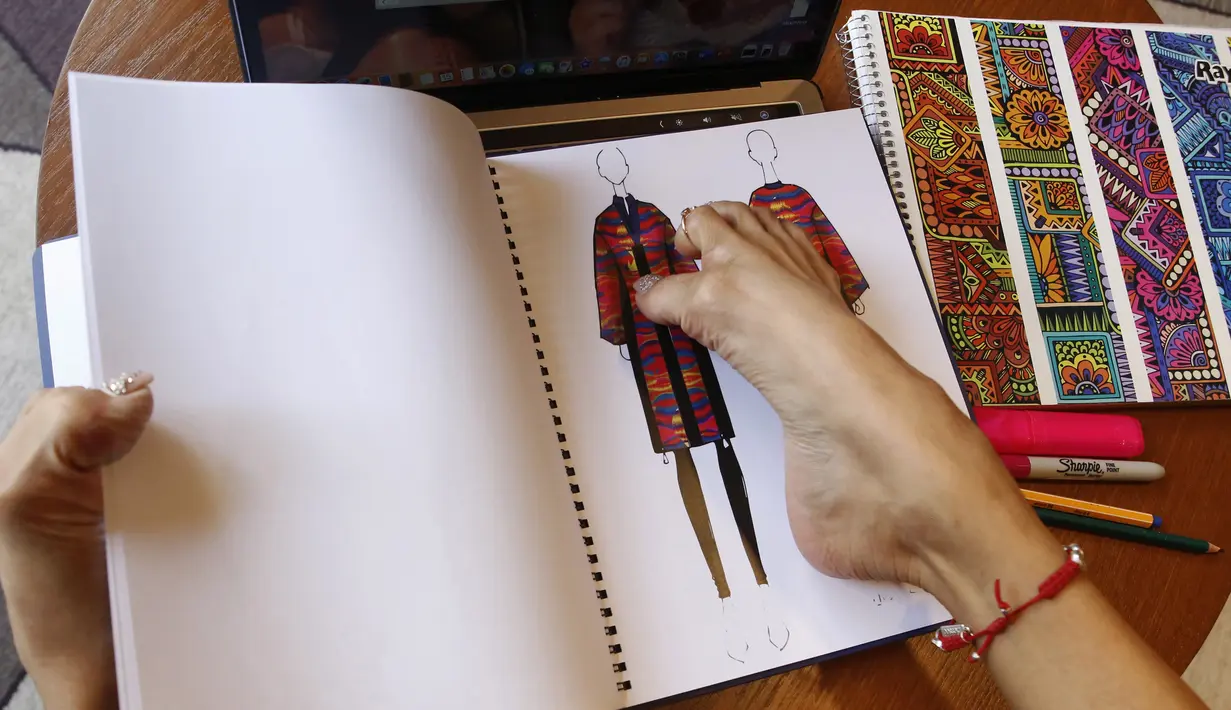 Adriana Macias menempelkan desain busana pada sebuah buku di Guadalajara, Meksiko, (15/5/2019). Desainer, yang juga seorang pengacara dan aktivis ini mengandalkan kaki untuk melakukan segala aktivitas, termasuk menggambar desain, memasak, hingga mengasuh anak. (AFP Photo/Ulises Ruiz)