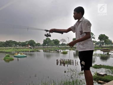 Seorang anak memancing di area banjir yang merendam TPU Semper, Jakarta, Selasa (4/12). TPU Semper menjadi langganan banjir saat musim penghujan akibat rendahnya permukaan tanah dengan ketinggian air sepinggang orang dewasa. (Merdeka.com/Iqbal S. Nugroho)