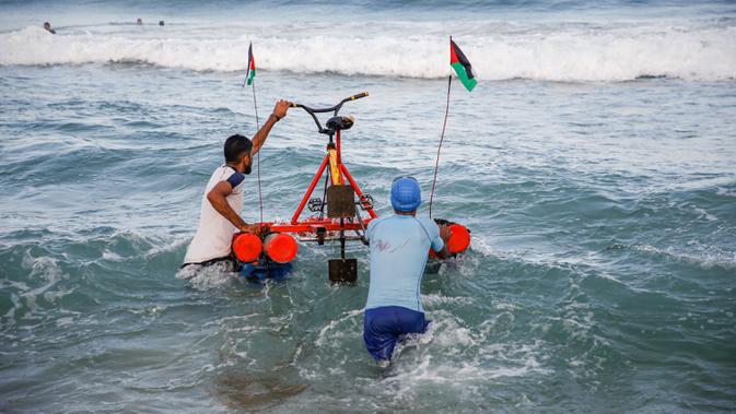 Nelayan Palestina membawa perahu kayuh yang dibuat khusus dari bahan daur ulang ke dalam air di sepanjang pantai di Beit Lahia, Jalur Gaza pada 29 September 2020. (Photo by MOHAMMED ABED / AFP)