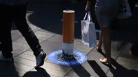 Sejumlah orang hilir mudik di sekitar puntung rokok raksasa di kawasan Pitt Street Mall, Sydney, Australia, Senin (26/9). Puntung rokok raksasa tersebut sebagai kampanye untuk kawasan bebas asap rokok di Sydney. (AFP PHOTO/Saeed Khan)