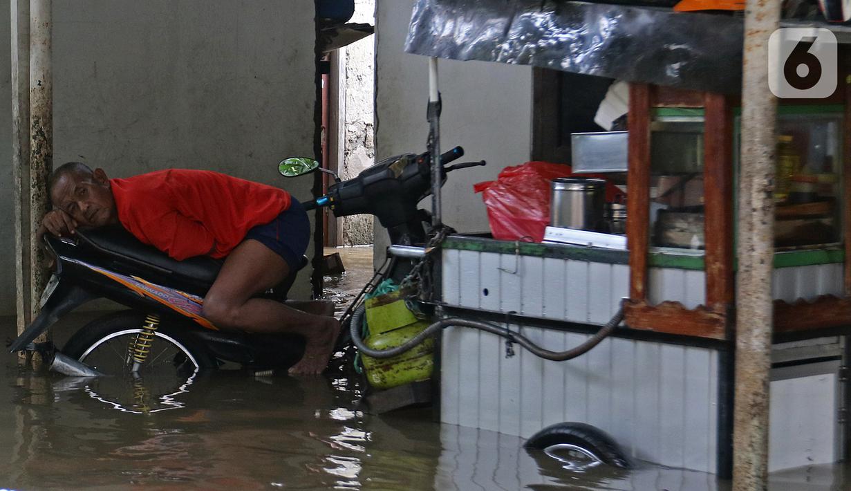 Warga tiduran di atas sepeda motor saat banjir di RW 07, Kelurahan Pekayon, Jakarta Timur, Sabtu (20/2/2021). Banjir di kawasan tersebut terjadi akibat curah hujan yang tinggi. (Liputan6.com/Herman Zakharia)