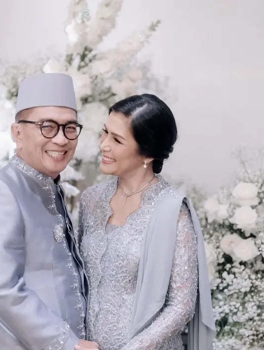 Helmy Yahya mengenakan beskap warna abu-abu dengan bros warna silver, lengkap menggunakan pecinya. Serasi dengan istrinya yang mengenakan kebaya abu-abu panjang dengan aksen selendang di bagian sisi lengannya dan kain sebagai bawahannya. [@bootesphotography]