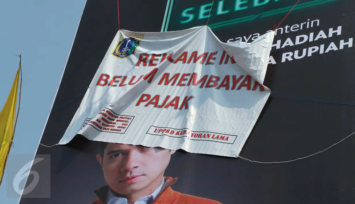 Sebuah reklame bergambar Dude Harlino tertutup spanduk di Kawasan Kebayoran Lama, Jakarta, Kamis (23/2). Reklame tersebut terkena razia oleh Satpol PP dan Dinas BP2T karena belum membayar pajak. (Liputan6.com/Gempur M Surya)