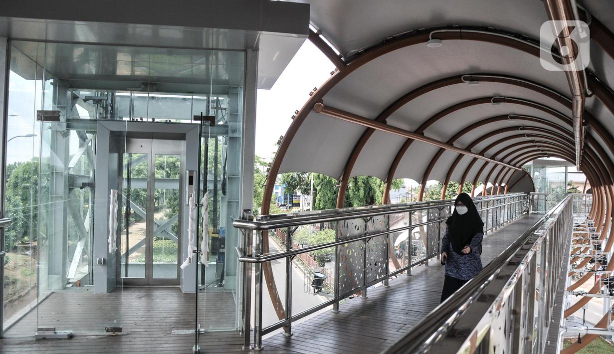 Pejalan kaki menggunakan fasilitas jembatan penyeberangan orang (JPO) di Jalan Kolonel Sugiono, Duren Sawit, Jakarta Timur, Senin (7/2/2022). JPO Kolonel Sugiono yang berada dekat Kanal Banjir Timur itu didesain dengan bentuk yang modern namun sarat kearifan lokal. (merdeka.com/Iqbal S Nugroho)