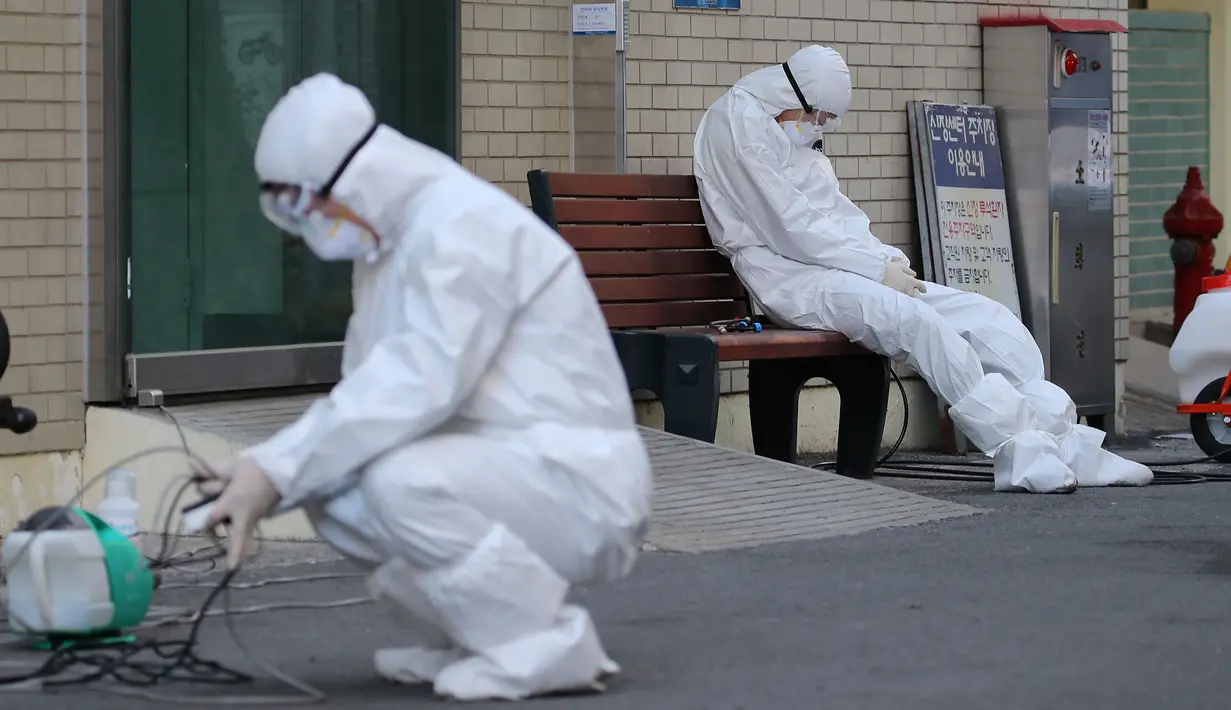 Petugas medis beristirahat saat menunggu pasien virus corona (COVID-19) di luar sebuah rumah sakit di Daegu, Korea Selatan, Minggu (23/2/2020). Korea Selatan mengonfirmasi 293 kasus baru virus corona pada 4 Maret 2020 sore. (YONHAP/AFP)
