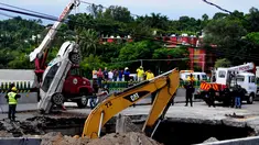 Tim penyelamat menggunakan derek untuk mengangkat sebuah mobil yang tertelan ke dasar lubang di jalan raya Meksiko-Cuenava, Meksiko, Rabu (12/7). Lubang yang tiba-tiba muncul itu membunuh seorang ayah dan putranya yang tengah berkendara. (AP/Tony Rivera)