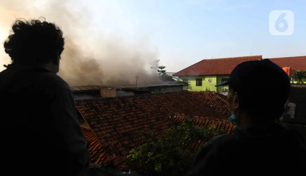 Asap hitam membumbung dari atas Gudang JNE Express yang terbakar di Jalan Pekapuran Raya, Depok, pada Senin (12/9/2022). Hingga berita ini diturunkan, proses pemadaman api masih berlangsung di gudang JNE di Depok. (Liputan6.com/Herman Zakharia)