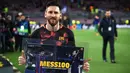 Striker Barcelona Lionel Messi berpose memegang poster saat merayakan golnya ke-100 di Liga Champions jelang pertandingan melawan AS Roma di Stadion Camp Nou di Barcelona (4/4). (AFP Photo/Filippo Monteforte)