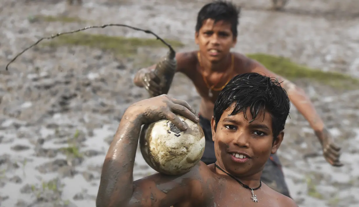 Dua orang anak berpose saat bermain permainan Kabaddi di sebuah lahan yang digenangi air di Kolkata (8/9/2019). (AFP Photo/Dibyangshu Sarkar)