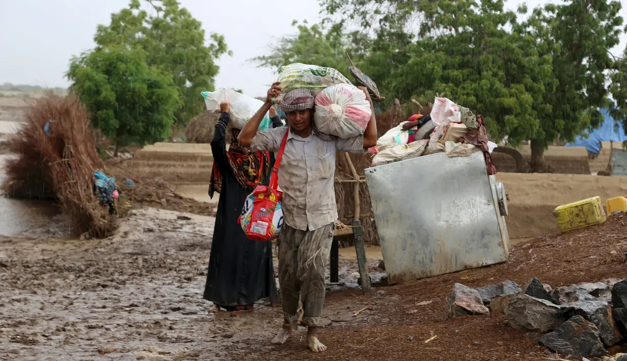 Sejumlah Warga membawa barang miliknya melintasi banjir setelah hujan deras melanda sebuah desa di provinsi Laut Merah Yaman, Houdieda, Jumat,  15 April 2016. (REUTERS/Abdul Jabbar Zeyad)