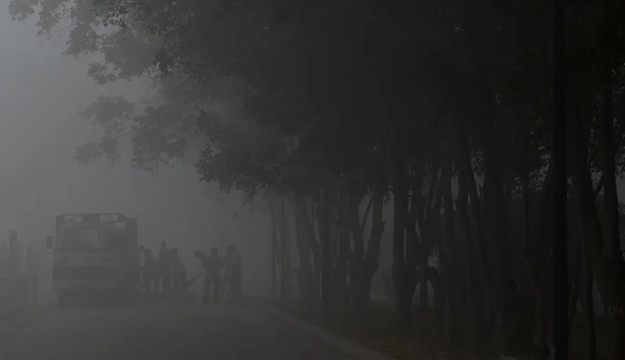 Para pekerja terlihat di tengah kabut asap tebal di New Delhi pada 22 Februari 2023. (Arun SANKAR/AFP)