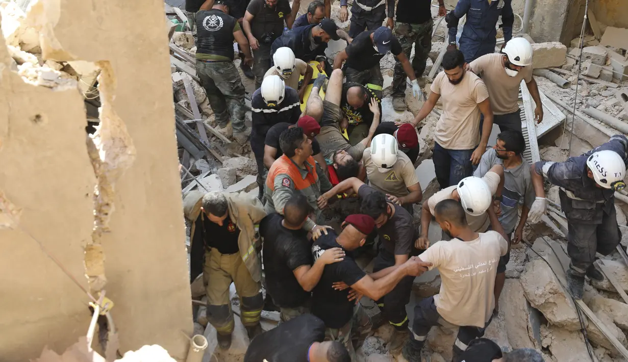 Tim penyelamat membawa korban selamat yang dikeluarkan dari puing-puing setelah ledakan besar di Beirut, Lebanon, Rabu (5/8/2020). Ledakan yang mengakibatkan puluhan orang tewas dan ribuan lainnya terluka tersebut meratakan pelabuhan dan merusak bangunan di seluruh Beirut. (AP Photo/Hassan Ammar)