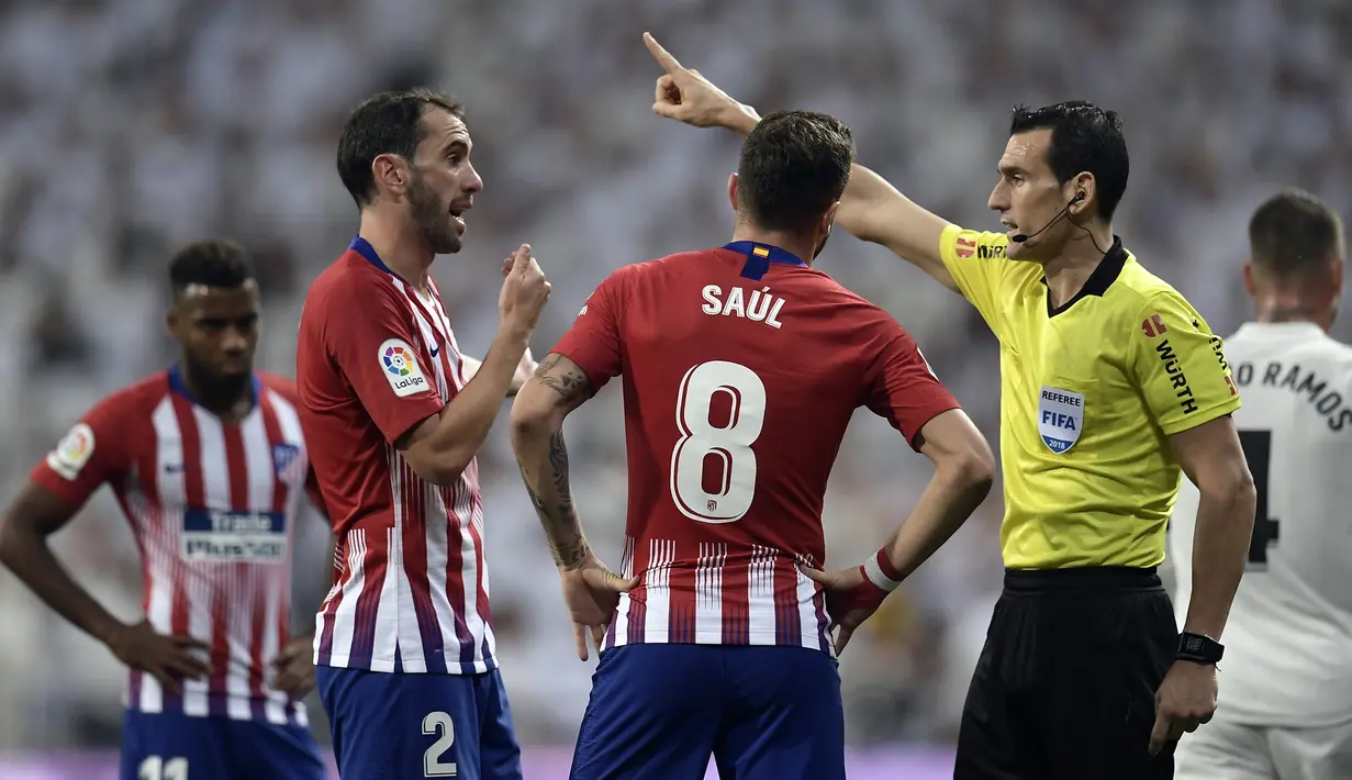 Wasit memberikan peringatan kepada bek Atletico Madrid, Diego Godin, saat melawan Real Madrid pada laga La liga di Stadion Santiago Bernabeu, Madrid, Sabtu (29/9/2018). Kedua klub bermain imbang 0-0. (AFP/Oscar Del Pozo)