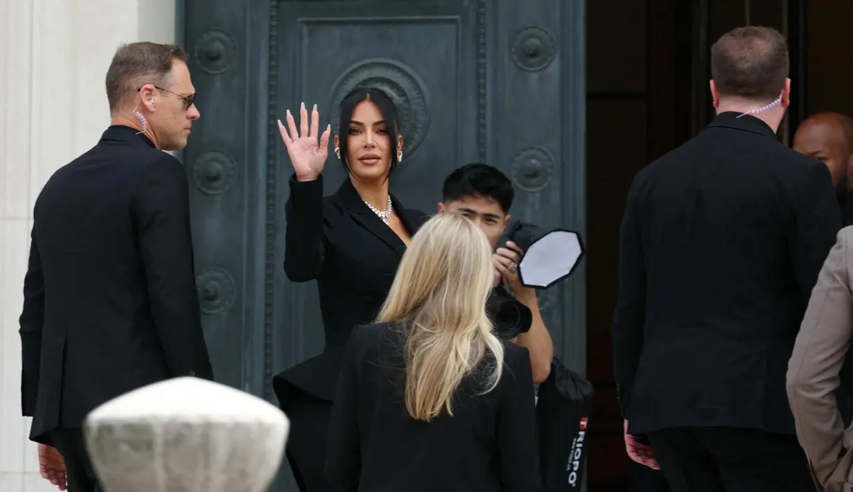 Pesohor asal Amerika Serikat (AS), Kim Kardashian (tengah) melambaikan tangan saat tiba di Pengadilan Assize, Paris, Prancis pada 13 Mei 2025. (Alain JOCARD/AFP)