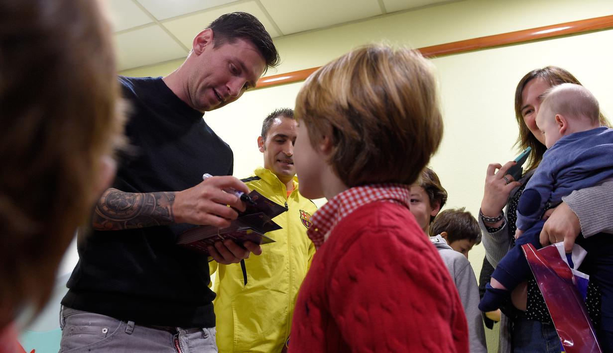 Bintang Barcelona, Lionel Messi memberikan tanda tangan untuk pasien anak-anak saat melakukan kunjungan amal di Rumah Sakit Barcelona, Senin (4/1/2016). (AFP PHOTO / Lluis GENE)