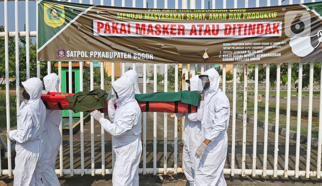 Petugas Satpol PP Kabupaten Bogor yang mengenakan pakaian hazmat menggotong warga pelanggar PSBB di kawasan Stadion Pakansari, Kabupaten Bogor, Jawa Barat, Minggu (6/9/2020). Pemkab Bogor menerapkan sanksi denda Rp 100 ribu serta sanksi sosial bagi pelanggar PSBB. (Liputan6.com/Herman Zakharia)