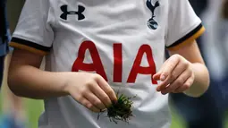 Seorang supporter Tottenham Hotspur membawa rumput yang diambilnya usai pertandigan di Liga Inggris di stadion White Hart Lane, London, (14/5). The Lilywhites akan bermarkas di Stadion Wembley sembari menunggu stadion baru jadi. (AP/Frank Augstein)