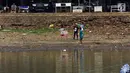 Sejumlah anak-anak bermain layang-layang di Setu Babakan yang sedang surut, Jakarta, Jumat (7/7). Menurut petugas, air sengaja disurutkan terkait proyek pengerukan di sekitar hulu Setu Babakan. (Liputan6.com/Helmi Fithriansyah)