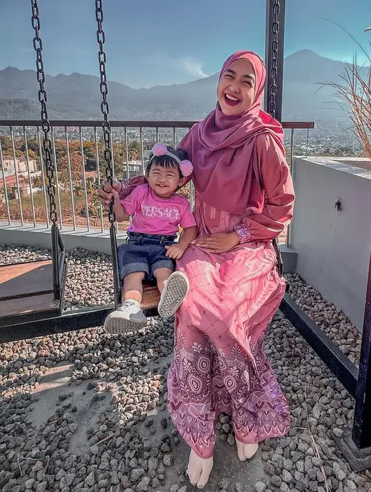 Moana juga tampil mengenakan kaos pink Versace yang serasi dengan bondunya. Dipadukan celana pendek dan sneakersnya. [@riaricis1795]