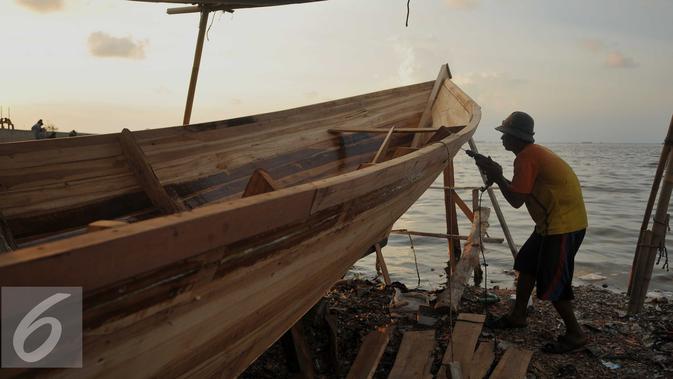 Pekerja mengebor kayu untuk pembuatan kapal kayu berjenis But Tempel di Cilincing, Jakarta, Selasa (9/8). Mahalnya harga kapal kayu berjenis But Tempel dikarenakan mahalnya harga kayu sebagai bahan baku utama. (Liputan6.com/Gempur M Surya)