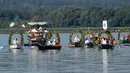 Warga Desa Moos memasuki Pelabuhan Radolfzell sambil manaiki kapal berhias bunga saat mengikuti Pawai Air Mooser di Danau Constance, Jerman, Senin (22/7/2019). Tradisi ini sudah berlangsung selama berabad-abad silam. (Patrick Seeger/DPA/AFP)